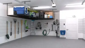 Storage A tidy garage, reminiscent of a Garage Kings Poto Gallery, features a variety of tools hanging neatly on the left wall, including a broom, rake, and shovel. Overhead, a storage rack holds a cooler and various boxes. On the right wall, there's a bike, a coiled hose, a step ladder, and a blue recycling bin.