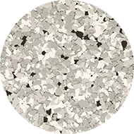 A circular image featuring a close-up of a terrazzo pattern. The surface contains variously sized, irregular pieces in shades of grey, white, and black, set within a lighter grey background, creating a speckled appearance.