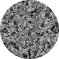 A circular image featuring a pattern of small, irregularly shaped chips in various shades of gray, from light to dark. The chips are closely packed, creating a textured, mosaic-like appearance.