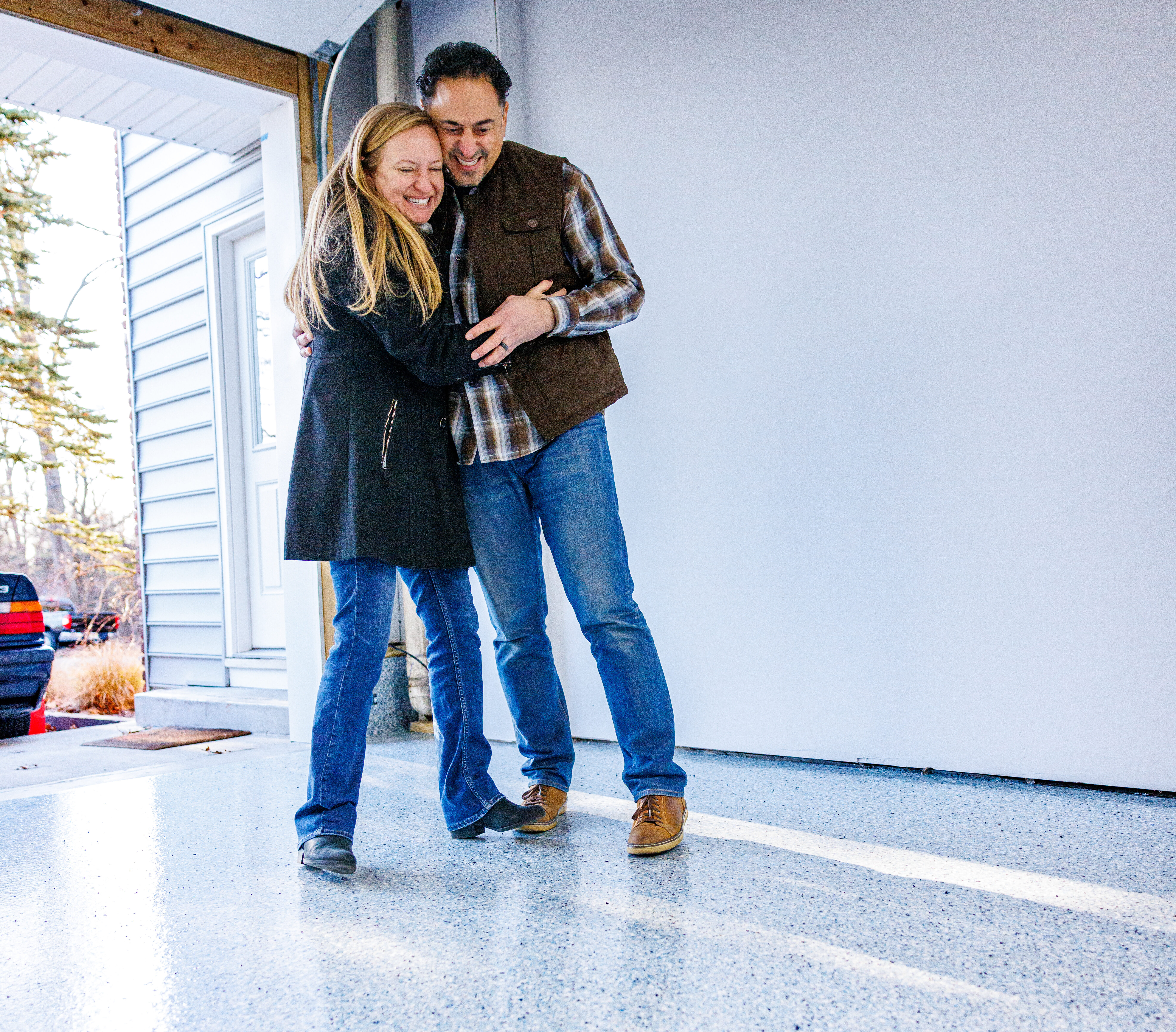 A couple smiling at their renovated garage flooring made by the Garage Kings franchise.